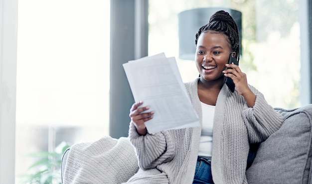 Un ottimo consiglio finanziario è solo una telefonata Inquadratura di una giovane donna che esamina le scartoffie e usa uno smartphone sul divano di casa