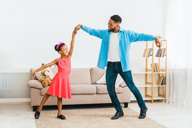 Un padre afroamericano che balla con la sua bambina.