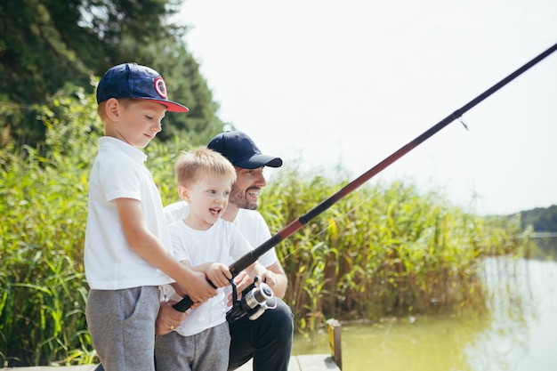 Un padre con due figli piccoli pesca nel lago d'estate nei fine settimana