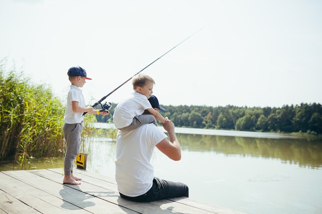 Un padre con due figli piccoli pesca nel lago d'estate nei fine settimana