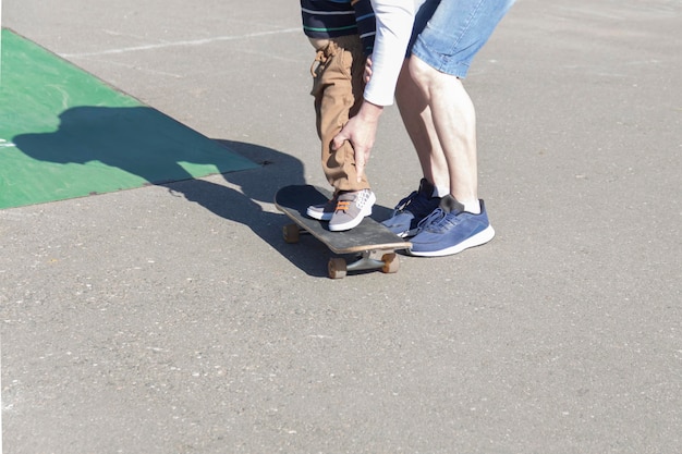 Un padre premuroso e amorevole insegna a suo figlio di tre anni a fare skateboard