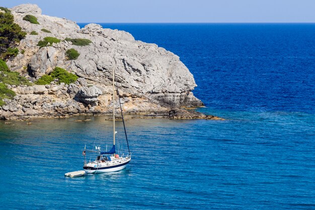 Un paesaggio di mare con yacht e roccia