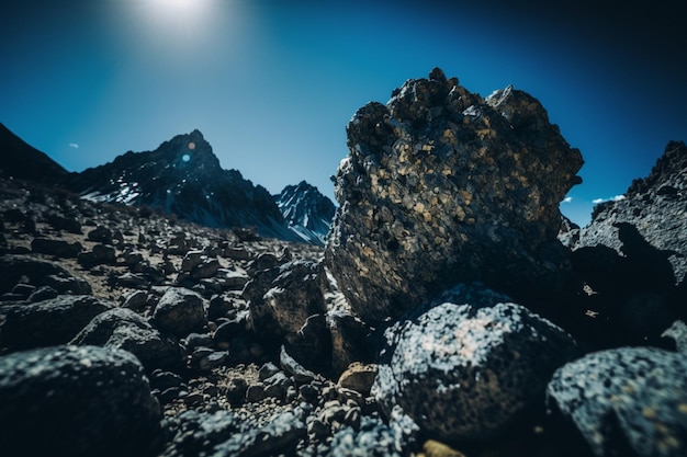 Un paesaggio di montagna con rocce e un cielo blu con il sole che splende su di esso.