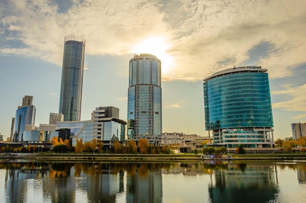 Un paesaggio urbano con un lago e un edificio alto con molte finestre e un cielo nuvoloso.