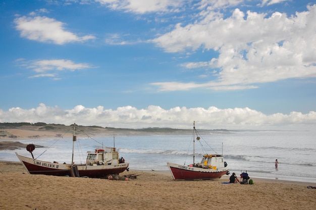Un paio di barche da pesca sulla sabbia della spiaggia di Punta del Diablo mentre una persona riposa sulla sabbia