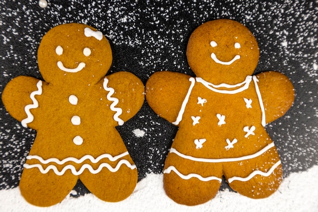 Un paio di biscotti di pan di zenzero su uno sfondo scuro con imitazione della neve