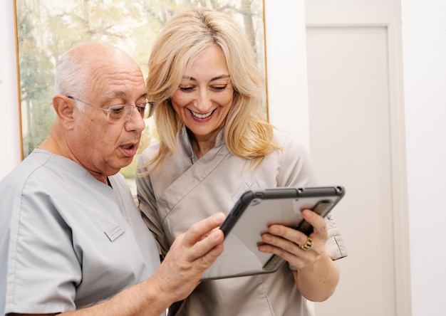 Un paio di dentisti consultano un tablet alla porta dello studio del dottore