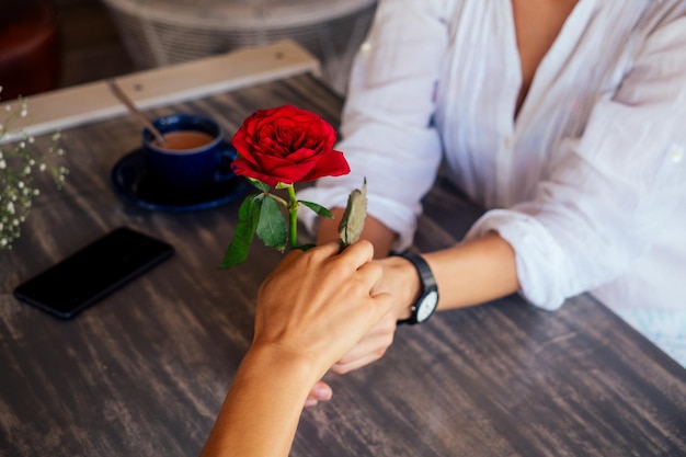 Un paio di donne trascorrono del tempo divertente insieme nel caffè estivo .girl dando una rosa alla sua fidanzata data di san valentino.