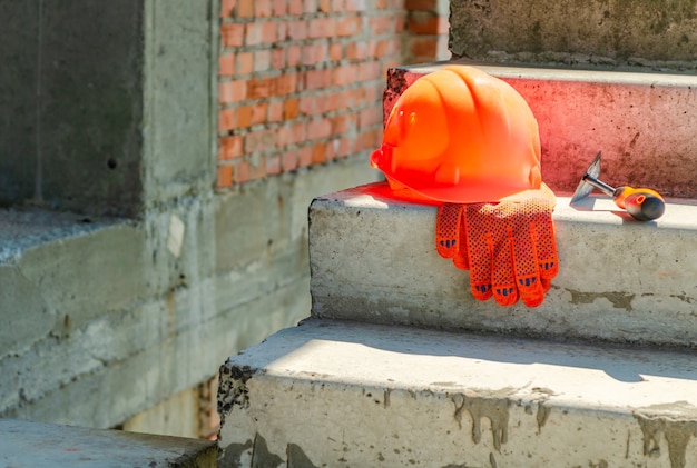 Un paio di guanti e un elmo da muratore nel cantiere di una casa di mattoni rossi.