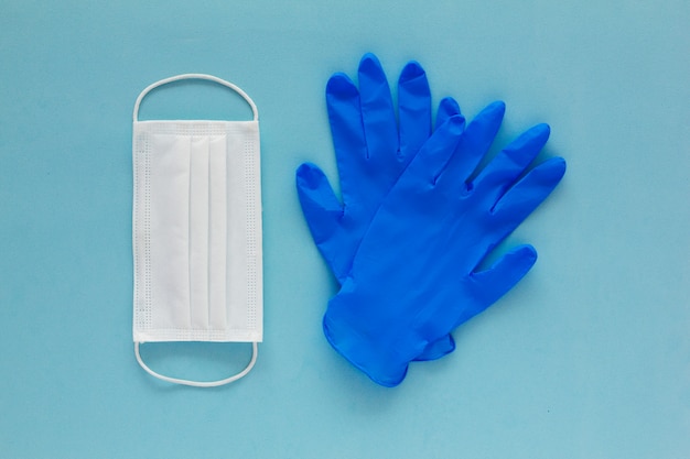 Un paio di guanti medicali e una maschera per il viso su uno sfondo blu con texture. Protezione contro il coronavirus
