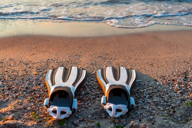 Un paio di pinne bianche e nere sulla sabbia della spiaggia