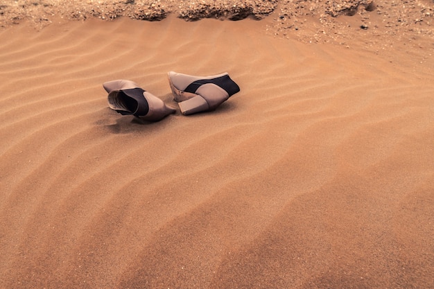 Un paio di scarpe da donna smarrite sulla sabbia tra le dune