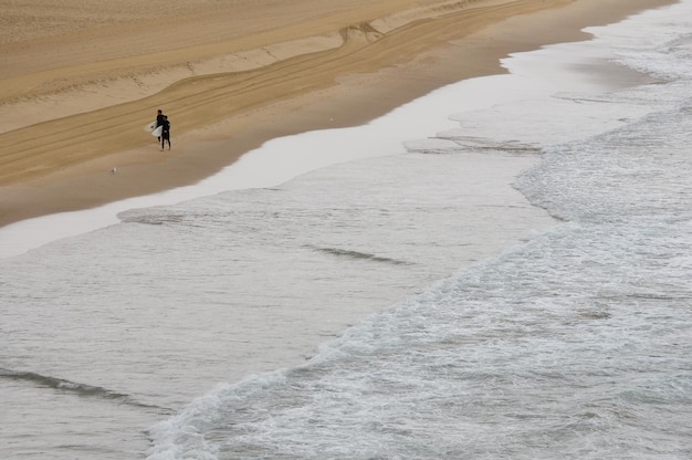 Un paio di surfisti camminano con le loro tavole da surf sulla spiaggia di Bondi Beach