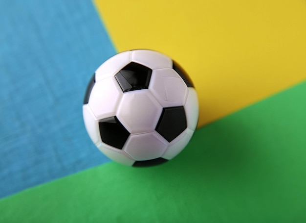 Un pallone da calcio bianco e nero si trova su una superficie colorata.