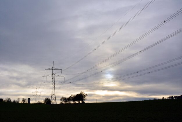 Un palo della linea elettrica sullo sfondo di un cielo serale luminoso e di piccole nuvole