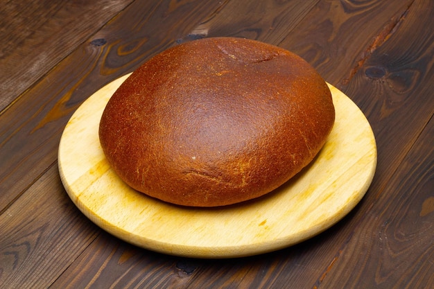 Un pane su un piatto di legno su un tavolo di legno Pagnotta di pane nero Pane fatto in casa al forno