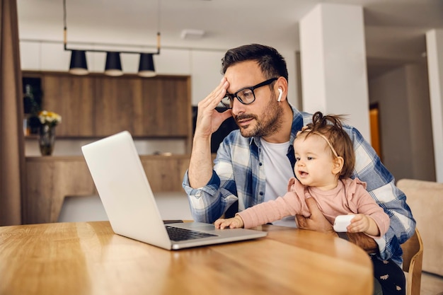 Un papà casalingo ha una teleconferenza con i colleghi mentre fa da babysitter alla sua bambina