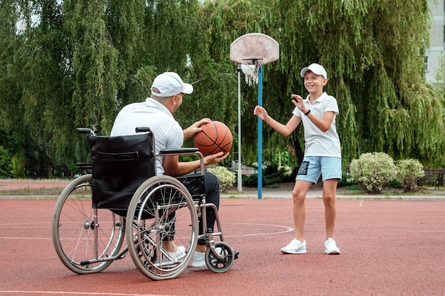 Un papà disabile gioca con suo figlio per strada. Concetto di sedia a rotelle, persona disabile, vita appagante, padre e figlio, attività, allegria.