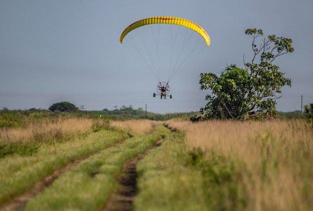 Un parapendio sorvola un campo erboso con un paracadute giallo.