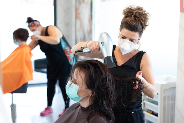 Un parrucchiere professionista che taglia i capelli a un cliente con una maschera per il viso