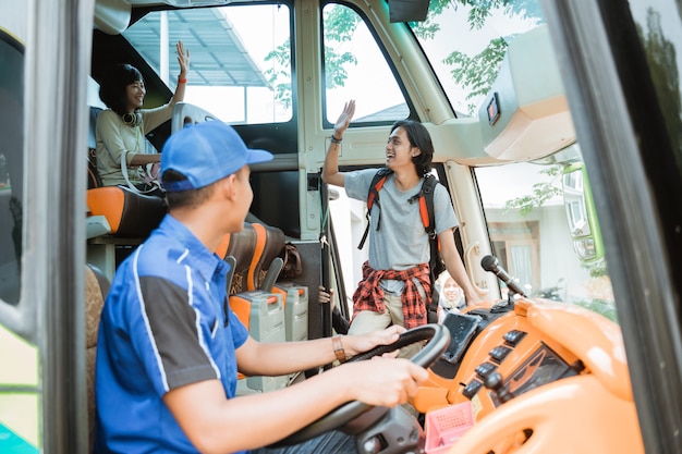 Un passeggero maschio è salito sull'autobus con una mano salutando quando ha incontrato il suo gruppo di amici a bordo dell'autobus