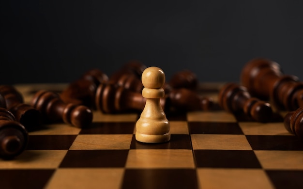 Un pedone bianco è il vincitore tra i pezzi degli scacchi neri caduti sulla scacchiera