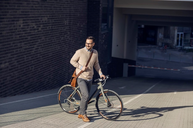 Un pendolare spinge la sua bicicletta per strada