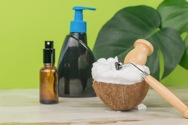 Un pennello e un rasoio in una ciotola con molta schiuma da barba e accessori per il lavaggio.