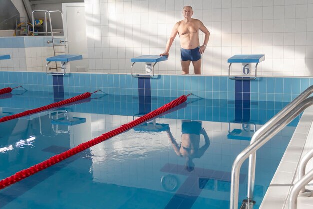 Un pensionato di 70 anni sta riposando nuotando riprendendosi nella piscina con acqua limpida e azzurra dell'hotel