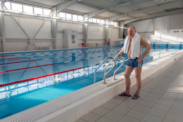 Un pensionato di 70 anni sta riposando nuotando riprendendosi nella piscina con acqua limpida e azzurra dell'hotel