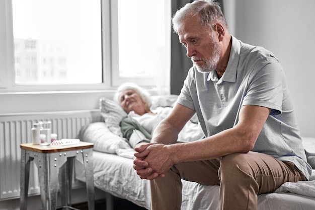 un pensionato sconvolto siede in depressione mentre la sua donna malata che soffre di covid-19, vuole che la moglie sia sana