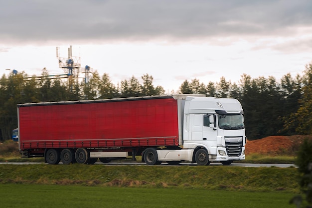 Un percorso panoramico diventa lo sfondo per un camion rosso che trasporta una consegna di merci su una strada un riflesso della catena logistica e del trasporto globale che collega il mondo