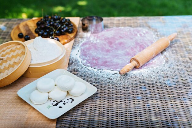 un perno rotante è su un tavolo accanto a una ciotola di mirtilli e una ciotoli di farina Mochi dessert asiatico