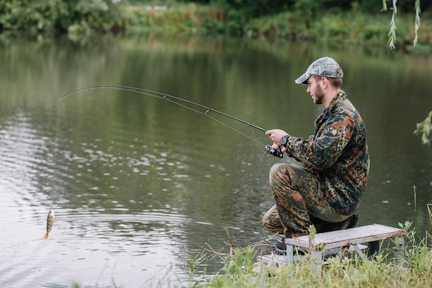 Un pescatore con una canna da pesca sulla riva del fiume