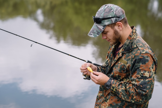 Un pescatore con una canna da pesca sulla riva del fiume