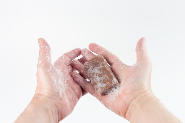 Un pezzo bagnato di sapone di catrame marrone in mani umane su sfondo bianco