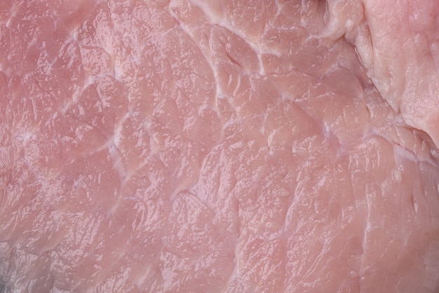 Un pezzo di carne di maiale cruda fresca e succosa con spezie ed erbe aromatiche su uno sfondo di cemento scuro