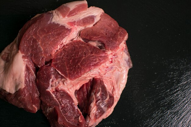 Un pezzo di carne di maiale cruda su sfondo nero