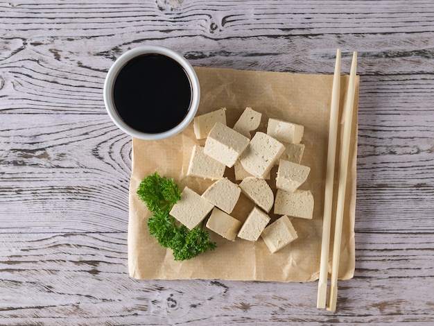 Un pezzo di carta stropicciata con salsa di soia e fette di formaggio tofu. Formaggio di soia