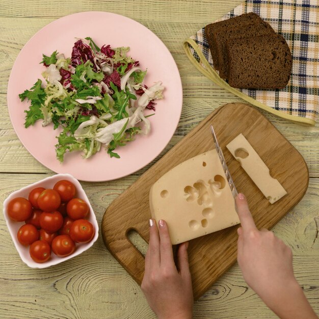 Un pezzo di formaggio e verdure fresche accanto a una superficie di legno Preparazione di un'insalata vegetariana