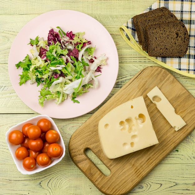 Un pezzo di formaggio e verdure fresche accanto a una superficie di legno Preparazione di un'insalata vegetariana