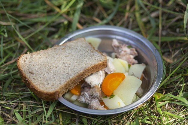 Un pezzo di pane e uno stufato con zuppa di patate Concetto di pausa pranzo durante il trekking trekking