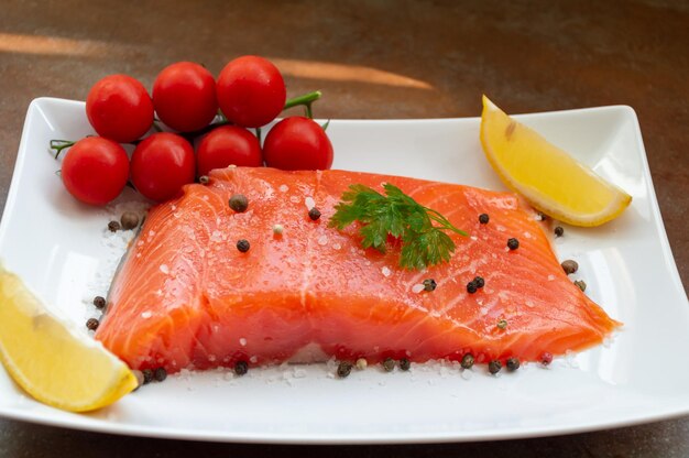 Un pezzo di salmone su un piatto con limone e pomodori