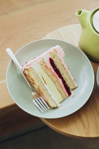 Un pezzo di torta di fragole e tè su un tavolo di legno in un caffè da vicino