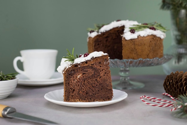 Un pezzo di torta di Natale sul piatto sul tavolo grigio con una tazza di tè e torta di Natale sul supporto di vetro