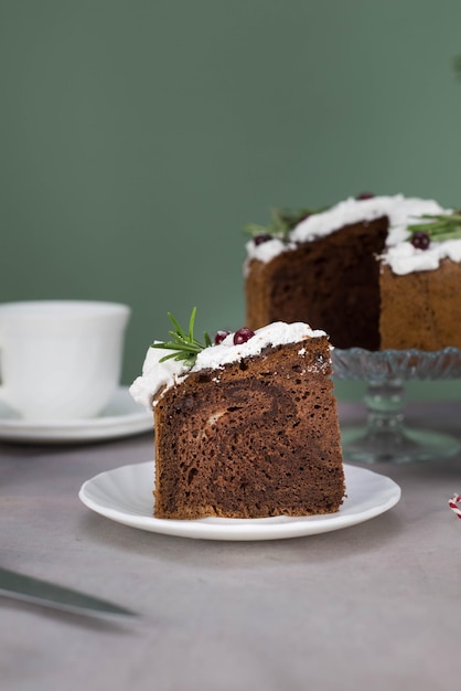 Un pezzo di torta di Natale sul piatto sul tavolo grigio con una tazza di tè e torta di Natale sul supporto di vetro