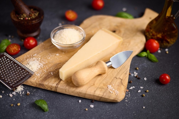Un pezzo di tradizionale formaggio duro parmigiano italiano su una tavola da taglio in legno nella cucina domestica