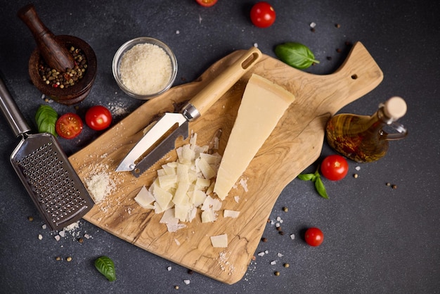 Un pezzo di tradizionale formaggio duro parmigiano italiano su una tavola da taglio in legno nella cucina domestica