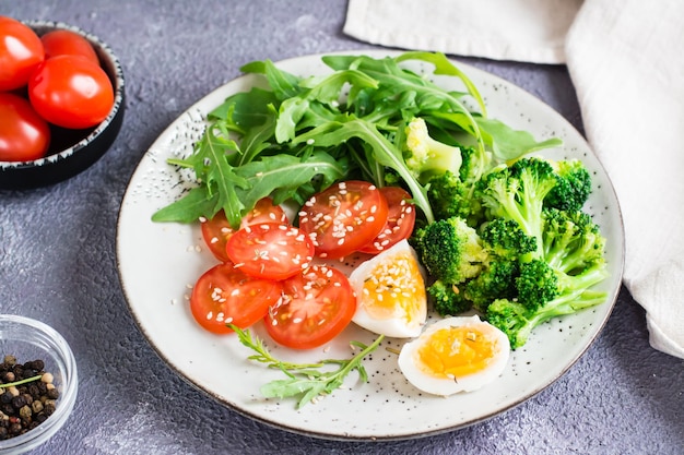 Un piatto con broccoli, rucola, pomodoro e uova sode su un piatto sul tavolo Primo piano