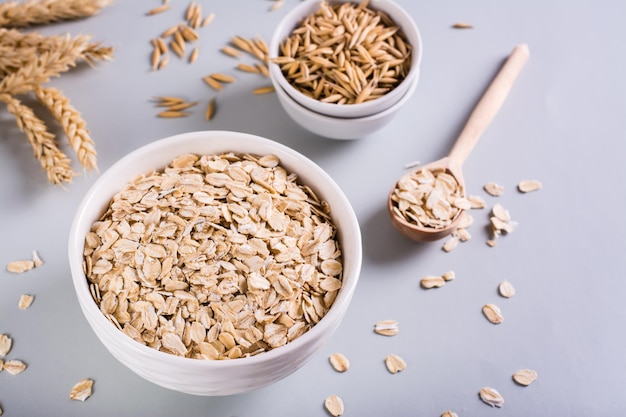 Un piatto con farina d'avena secca e spighe d'avena su sfondo grigio